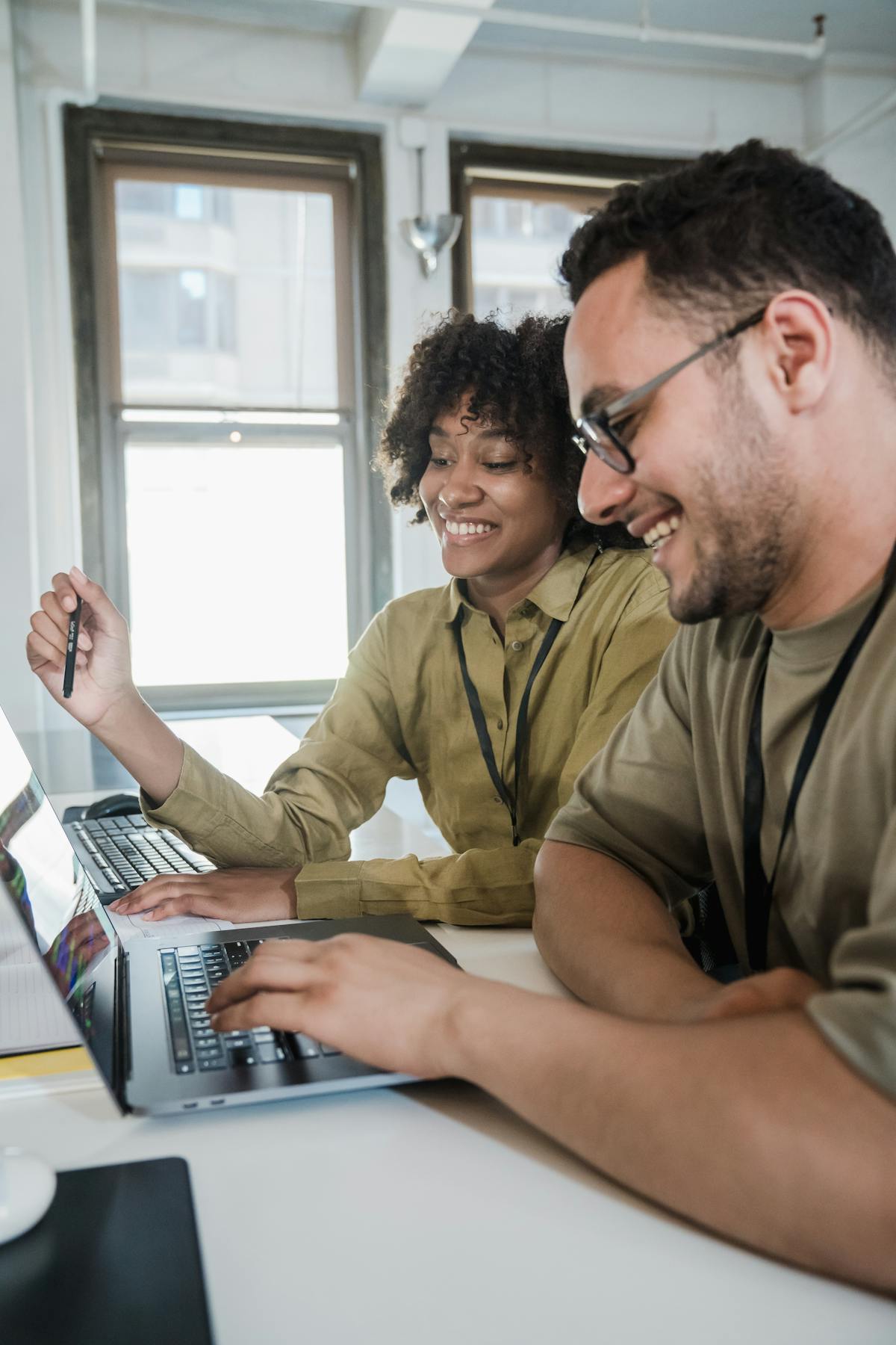 Two colleagues smiling while working together on laptops